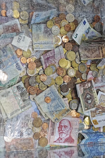 Mix coins and banknotes currency in clear donation money box