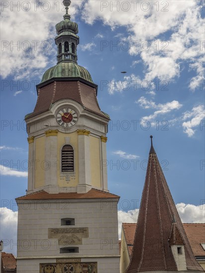 A towering clock tower and a steep church spire against a cloudy sky, Dürnstein, Wachau, Danube,