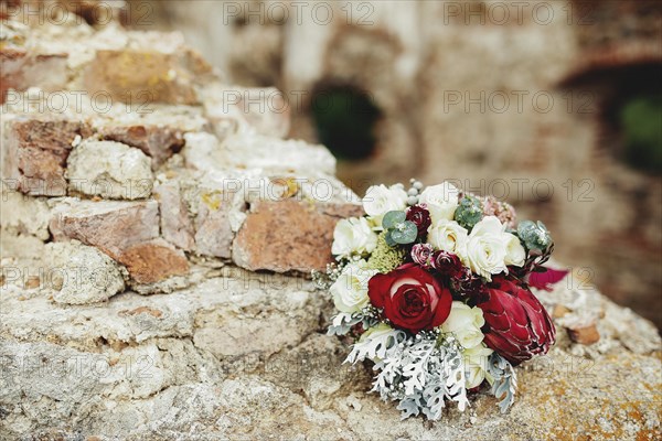 Wedding bouquet on the broken brick fence. Blurred background.