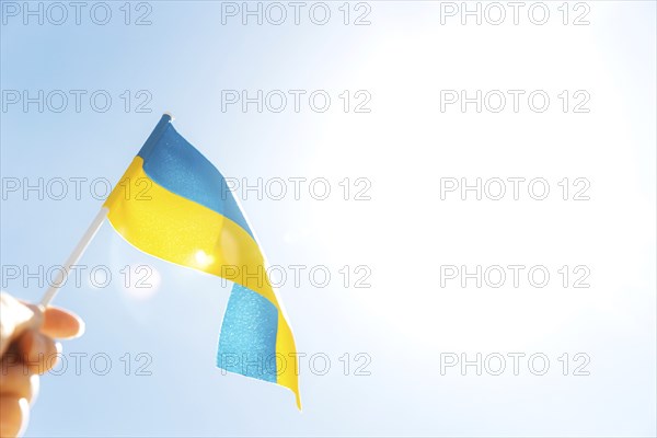 Human hand holding large bicolor yellow blue Ukrainian state flag, national symbol fluttering,