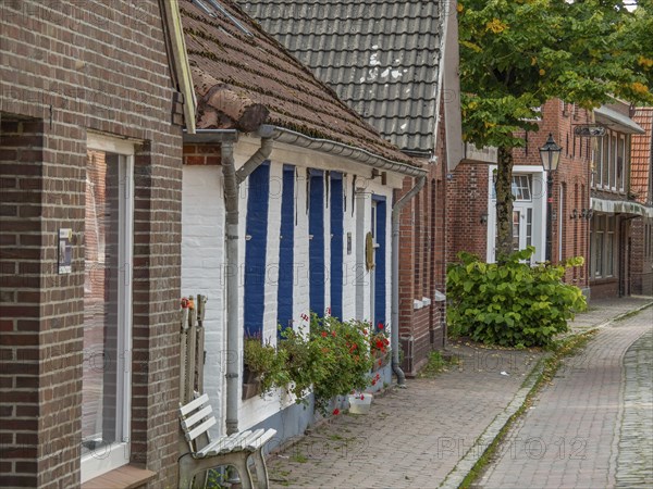 Street with traditional old houses made of brick and wood, decorated with flowers, dornum, east