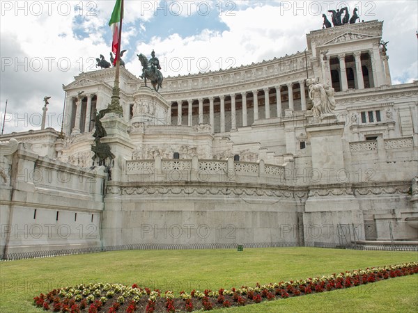 Side view of the Altar of the Nation in Rome with Italian flag and manicured lawn, rome, italy