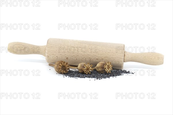 Dried poppy pods and poppy seeds in front of the rolling pin isolated on white background, full