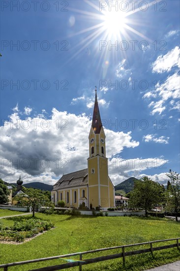 Church at Schliersee in Bavaria Germany with sun and blue sky in front of wooded mountains