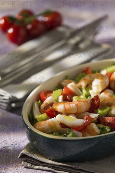Shrimp salad with squid tomatoes celery inside an oval bowl