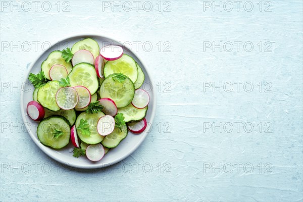 Fresh cucumber and radish salad with parsley, overhead flat lay shot. Simple vegan recipe on a
