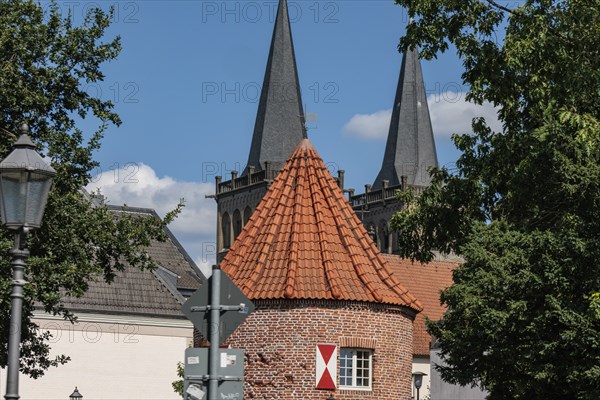 Historic brick building with striking towers and trees under a blue-green sky, Xanten, Lower Rhine,