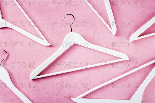 Fashion collection concept. White wooden hangers, a flat lay layout on pink. Shopping background,