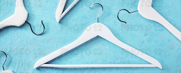 Fashion collection panorama. White wooden hangers, a flat lay layout on blue. Shopping background,
