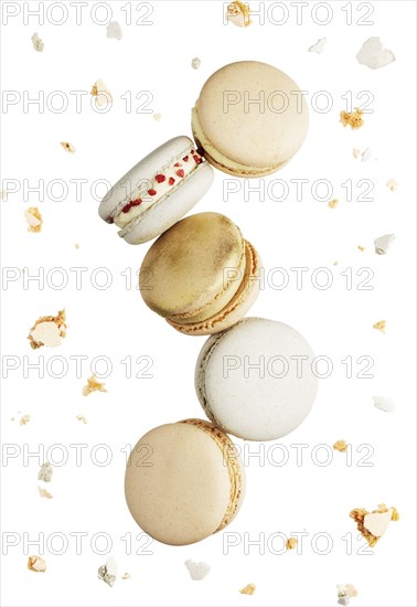 Isolated on white background white, yellow, gold macaron cookies flying, falling in motion or