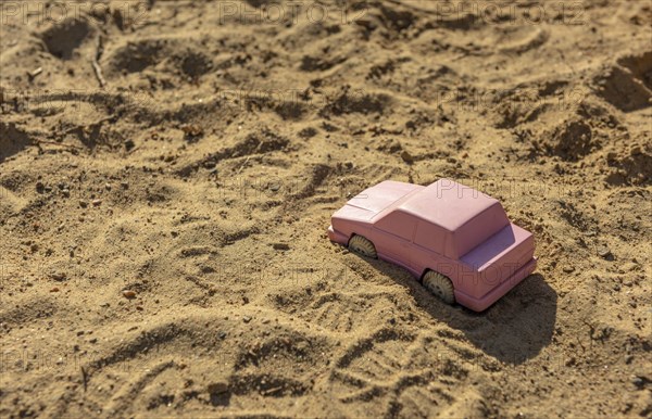 Pink toy car in the sand at a playground