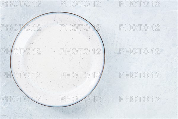 An empty white plate with a blue rim, overhead flat lay shot on a slate background, with copy
