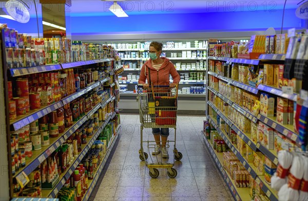 Woman wearing a face mask while shopping in a supermarket, Corona crisis, pandemic,