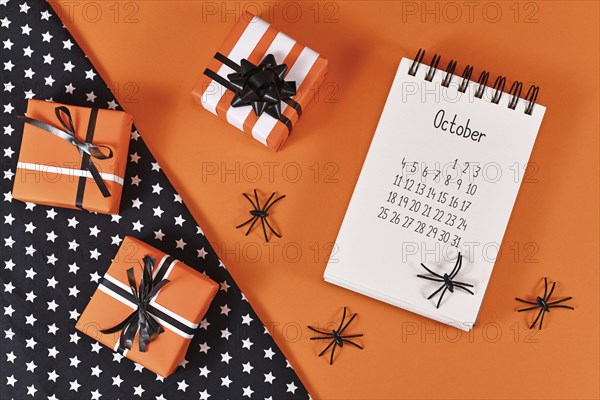 Calendar sheet for month October with Halloween spiders and gift boxes on orange and black
