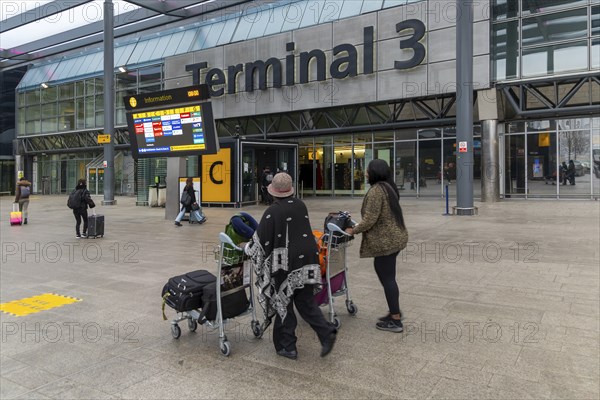 Passengers with luggage outside Terminal 3 building, London Heathrow Airport, England, UK