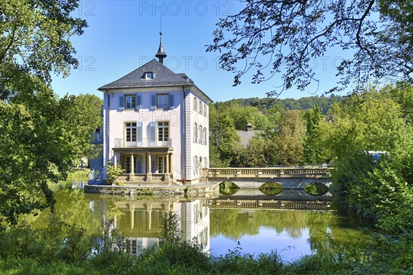 Small cultural heritage baroque castle building called Trappenseeschloss in middle of lake in