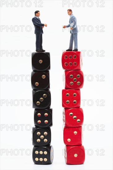 Symbol photo, two men (figure) standing perplexed on a stack of dice each showing the values 1 to 6