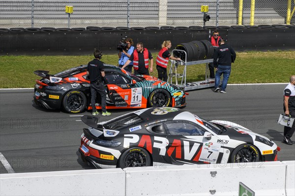 Team manager of car racing team and mechanic with spare tyres next to racing car Sports car Porsche