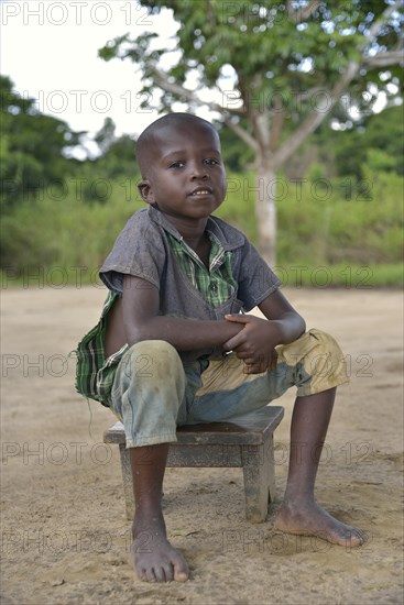 Boy sitting on a stool, Nkala, Bandundu Province, Democratic Republic of the Congo
