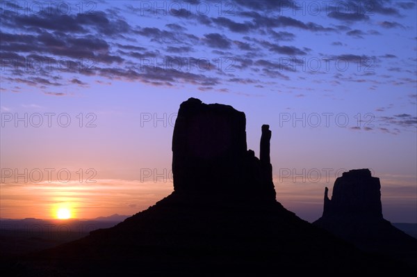 Eroded sandstone rock formations, buttes the Mittens silhouette at dawn in Monument Valley Navajo