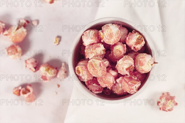 Top view of pink colored strawberry flavored sweet popcorn in white bowl