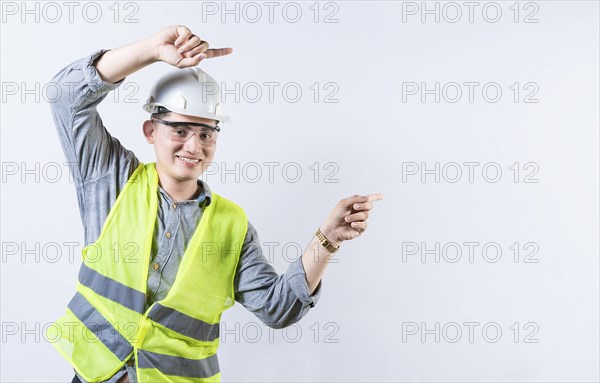 Portrait of smiling engineer pointing aside isolated. Handsome engineer pointing an advertisement