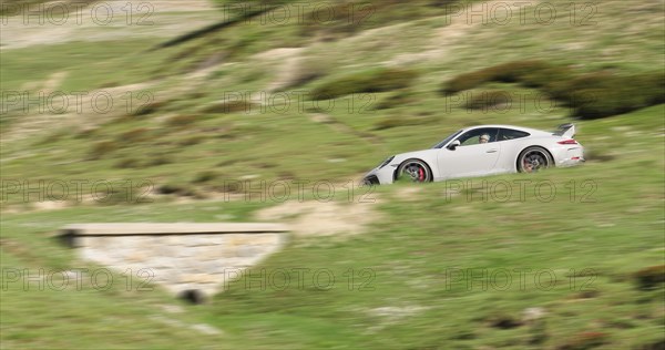 Speed effect photo of sports car Porsche GT3 driving on mountain road in Hocchalpen,