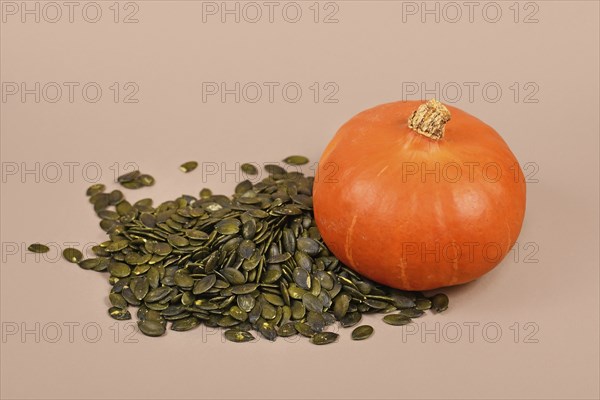 Pumpkin seeds next to whole 'Red Kuri Hokkaido' squash