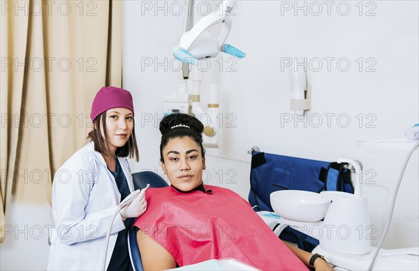 Portrait of young dentist with female patient in medical office, Female dentist with female patient