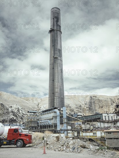 Chimney of the smelter, in the foreground a spoil heap contaminated with heavy metal residues, La