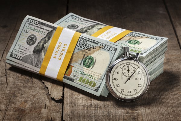 Time is money loan concept background, stopwatch and stack of new 100 US dollars 2013 edition