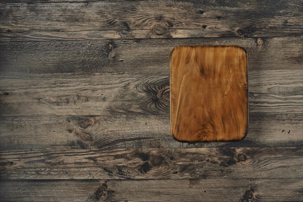 A beautifully crafted wooden cutting board is placed on a rustic wooden table, showcasing its