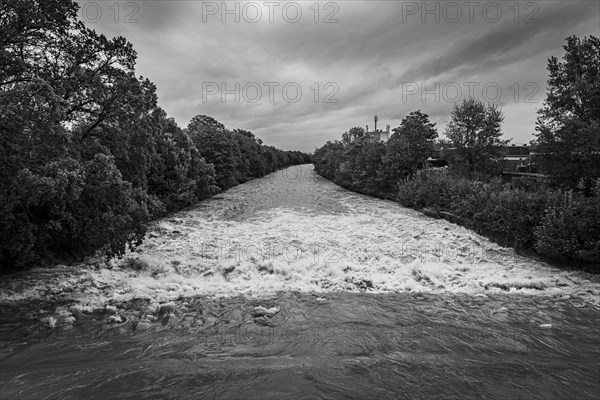 A powerful river with a strong current under a cloudy sky, surrounded by green trees, Schwarza,