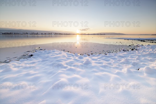 Snow-covered lakeshore in the peaceful atmosphere of a winter sunset, Seegarten, Allensbach, Lake