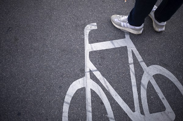 Close-up, shoes, sneakers, pedestrian standing on cycle path, marking, labelling, pictogram,
