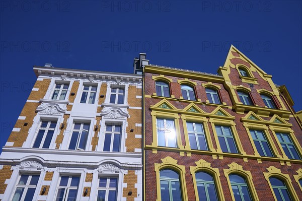A historic building with an elaborate façade and many windows, surrounded by a clear blue sky,
