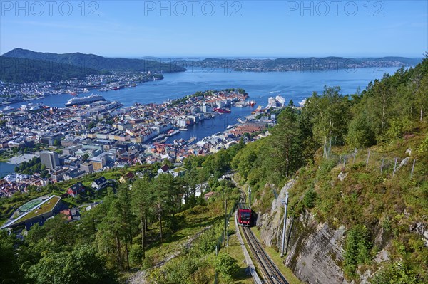 Panoramic view of Bergen with harbour on a clear day, cable car ascending the wooded mountain,