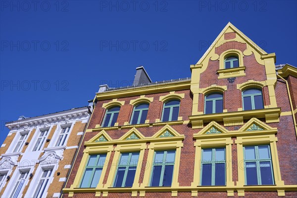 A historic building with an elaborate façade and many windows, surrounded by a clear blue sky,