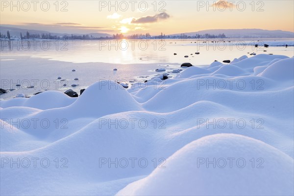 Snow-covered stones on a wintry lake at sunrise, clouds in the sky, Seegarten, Allensbach, Lake