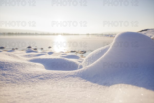 Snow covers the ground as the sun sets over a wintry lake, Seegarten, Allensbach, Lake Constance,