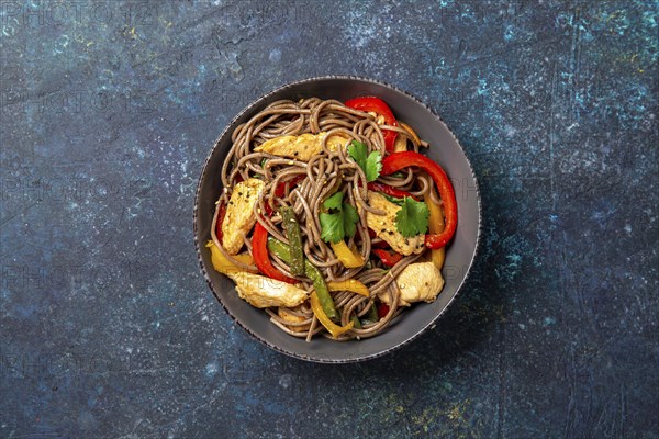 Japanese dish buckwheat soba noodles with chicken and vegetables carrot, bell pepper and green