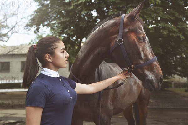A young girl talking and takes care of her horse. She loves the animals and joyfully spends her