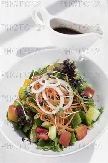 Fresh organic mixed vegetable vegan Garden Salad with Vinaigrette sauce on white table