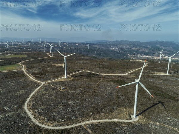 Aerial view of lot of windmills or wind turbine on wind farm in rotation to generate electricity