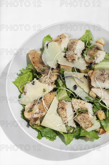 Organic chicken caesar salad with parmesan cheese and croutons on white table background