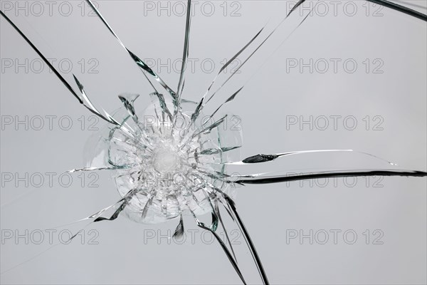 Broken window with cracks from impact or shot. Texture of cracks and chips on car windshield,