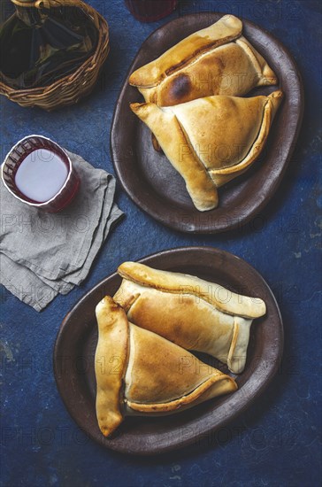 Food, Tipical Chilean baked empanadas de pino y napolitano on clay plates with wine. Dish and drink