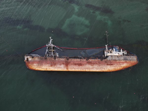Top view of an old tanker that ran aground, overturned and polluted the coast with oil spilled from