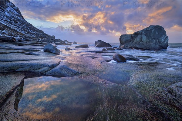 Rocks on beach of fjord of Norwegian sea in winter on sunset. Utakliev beach, Lofoten islands,