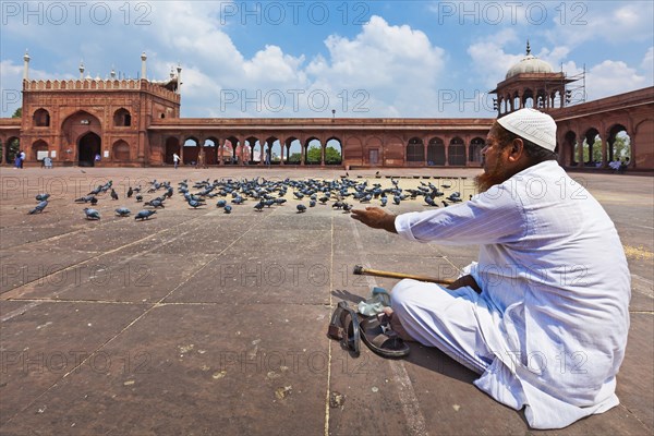 DELHI, INDIA, AUGUST 29, 2011: Muslim man feeding pigeons in India largest mosque Jama Masjid.